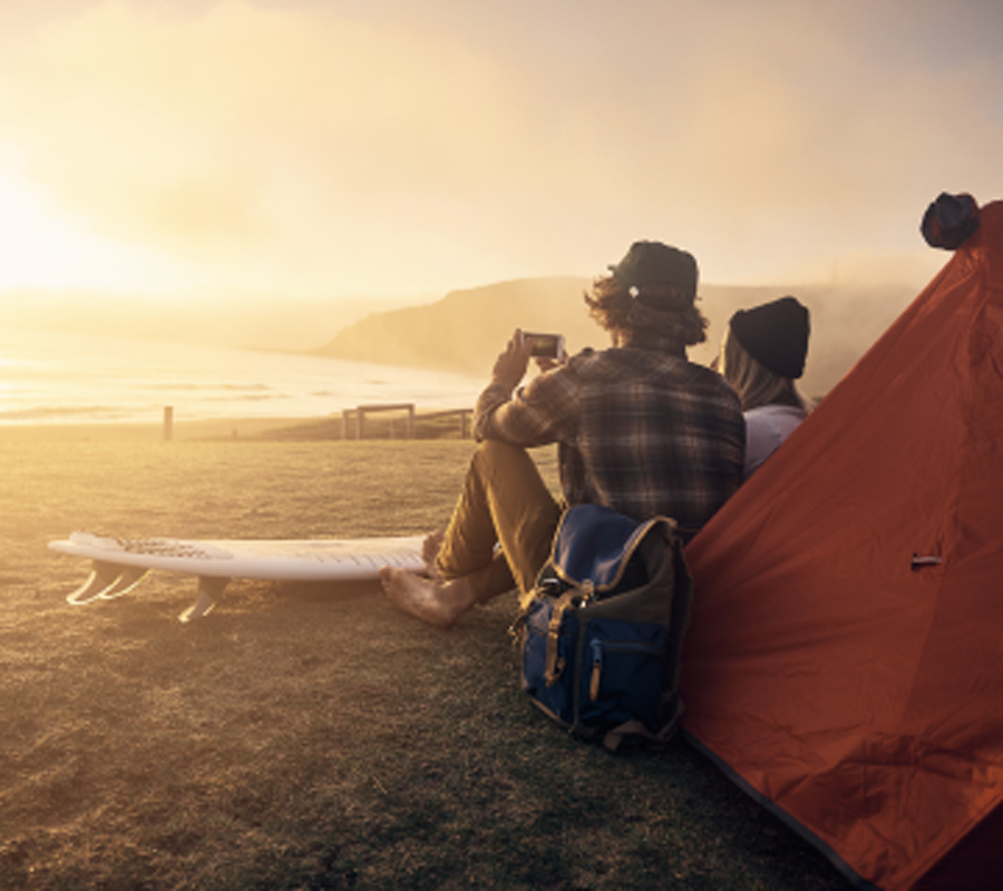 两个人坐在沙滩上的帐篷旁拍日出的照片.